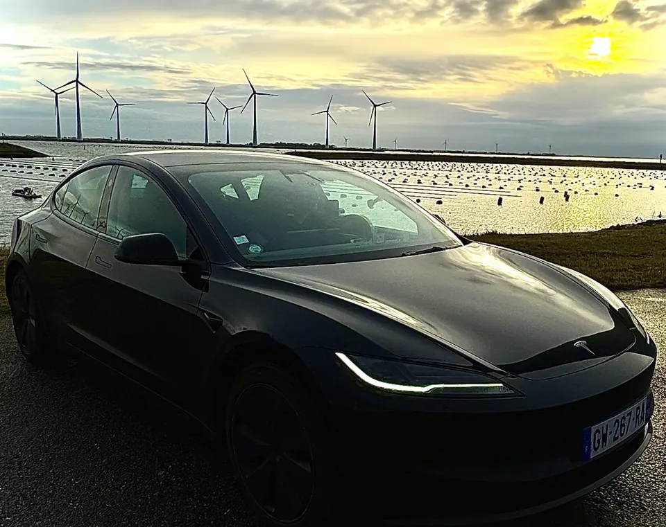 Tesla Model 3 noire EVASION VTC sur la côte du Finistère au lever du soleil, éoliennes et parcs à huîtres