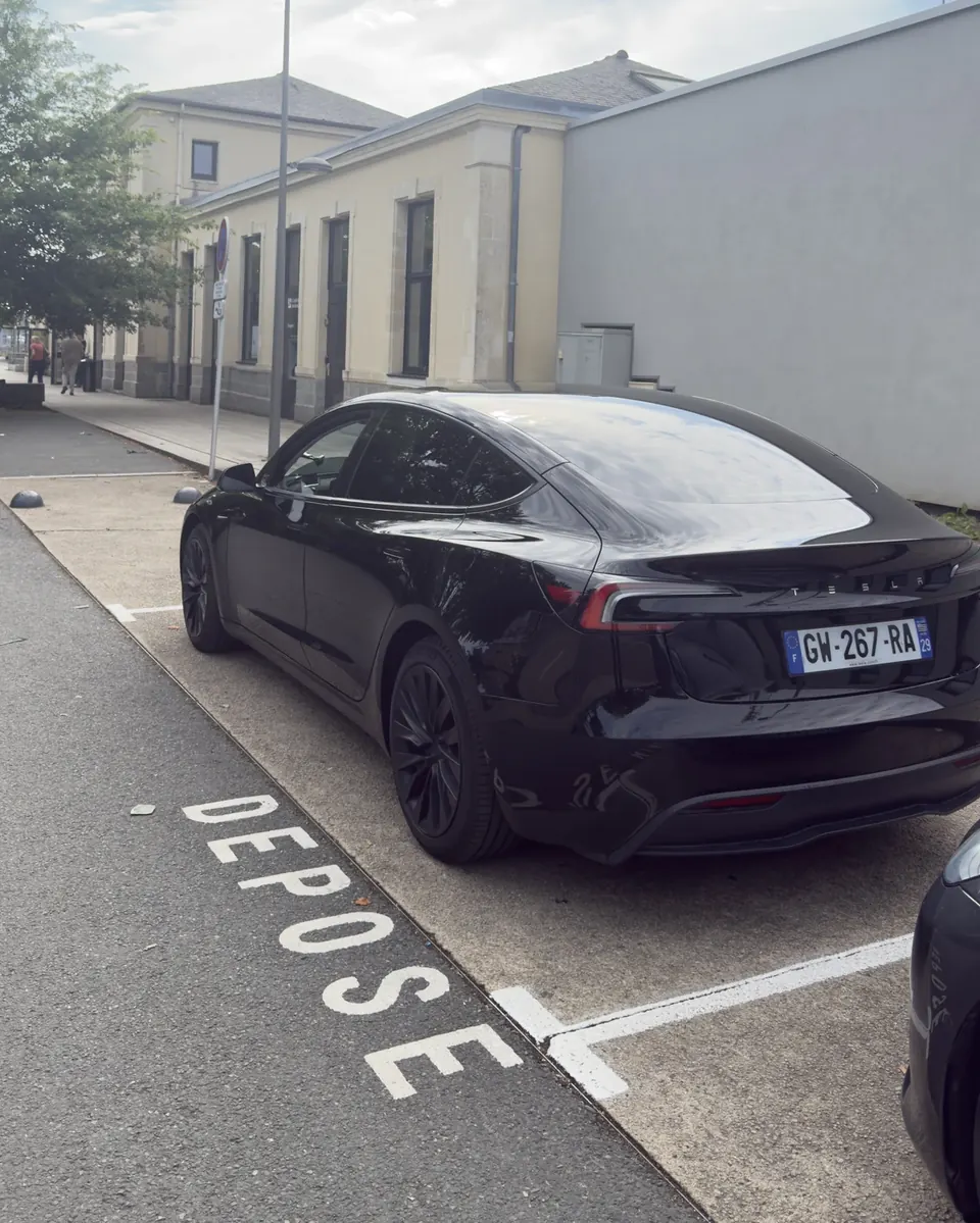 Tesla Model 3 noire EVASION VTC stationnée sur la zone dépose-minute devant une gare SNCF du Finistère