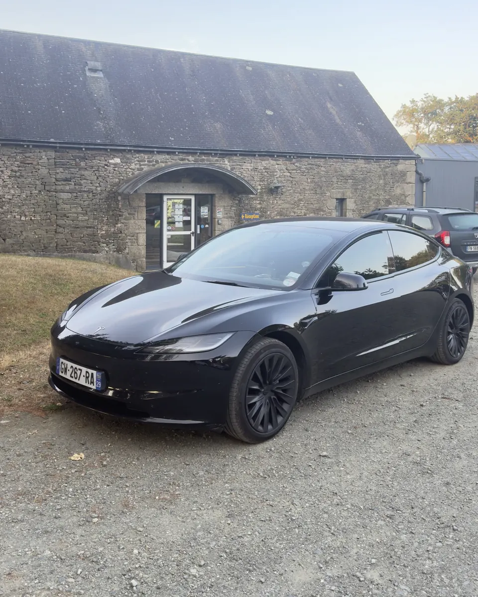 Tesla Model 3 EVASION VTC déposant des clients devant la réception d'un hôtel en pierre du Finistère